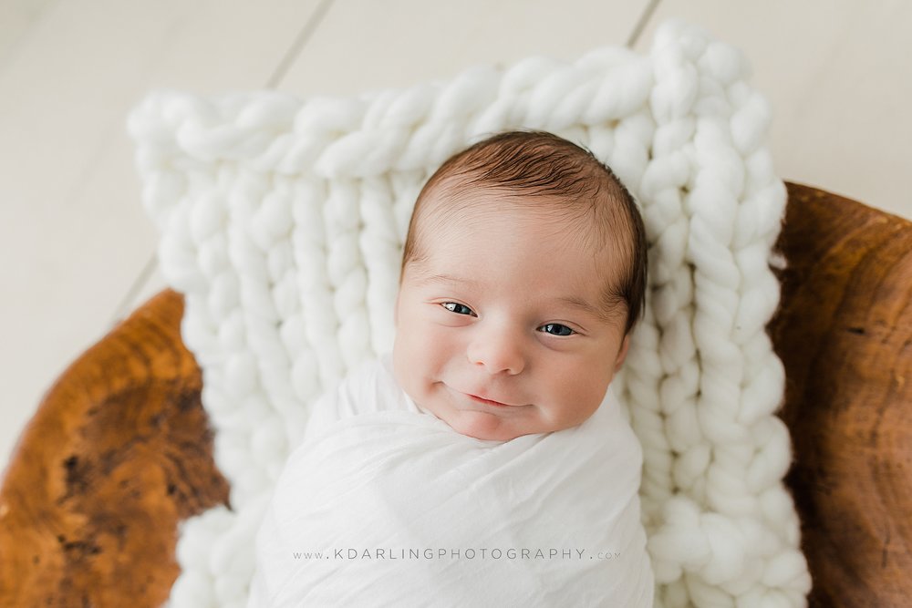 Smiling newborn baby boy in white with dough bowl