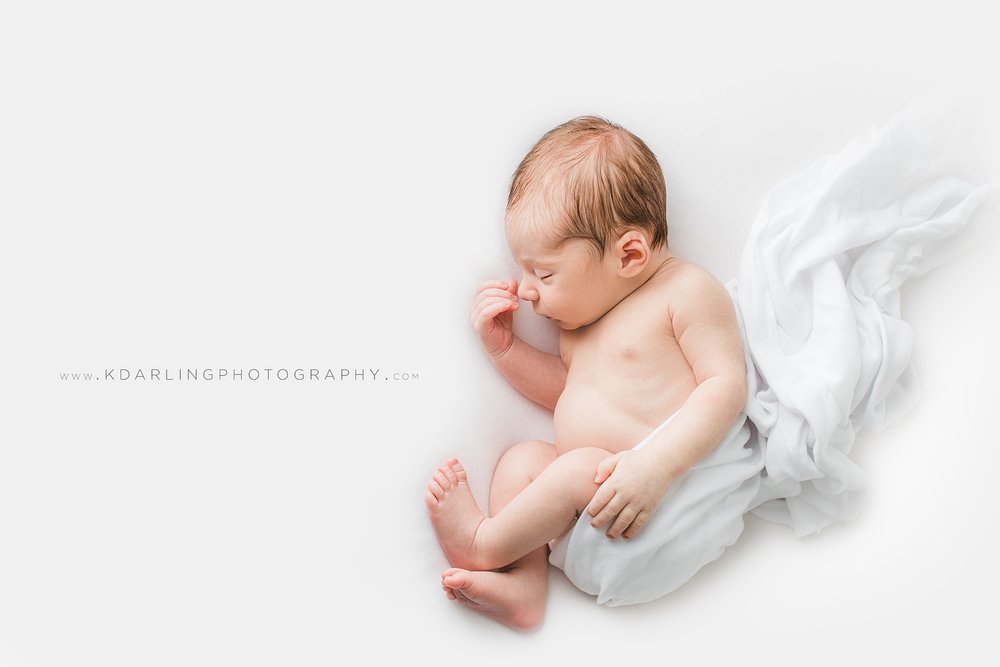 Sleeping newborn baby boy in all white