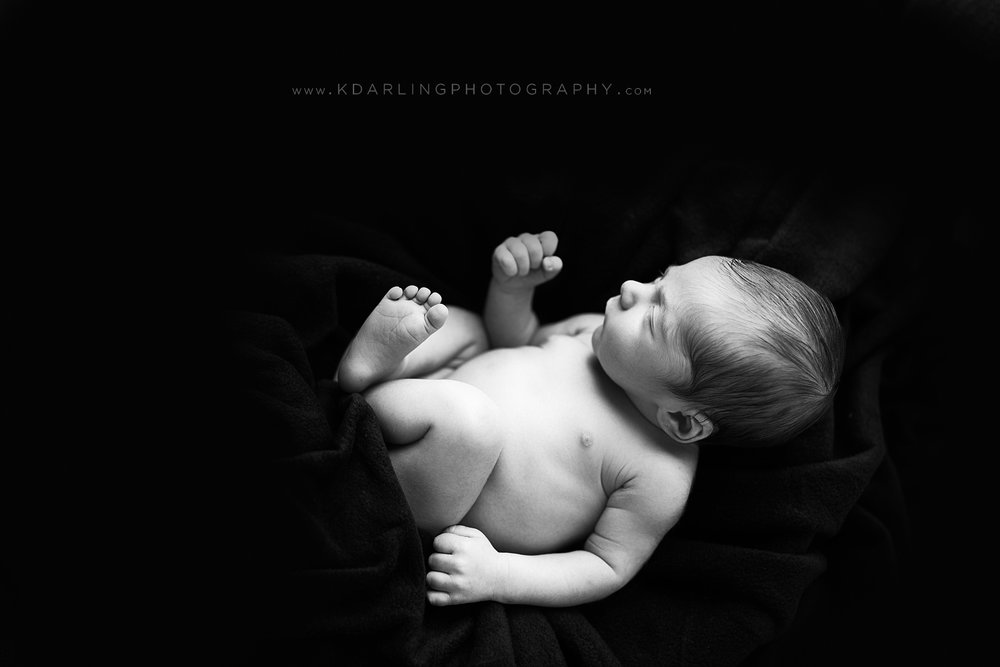 Newborn baby boy photographed on black background