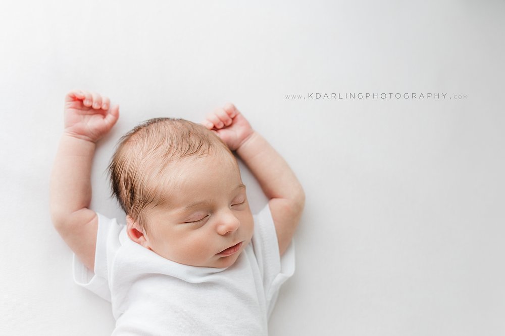 Newborn baby boy sleeping with hands above head