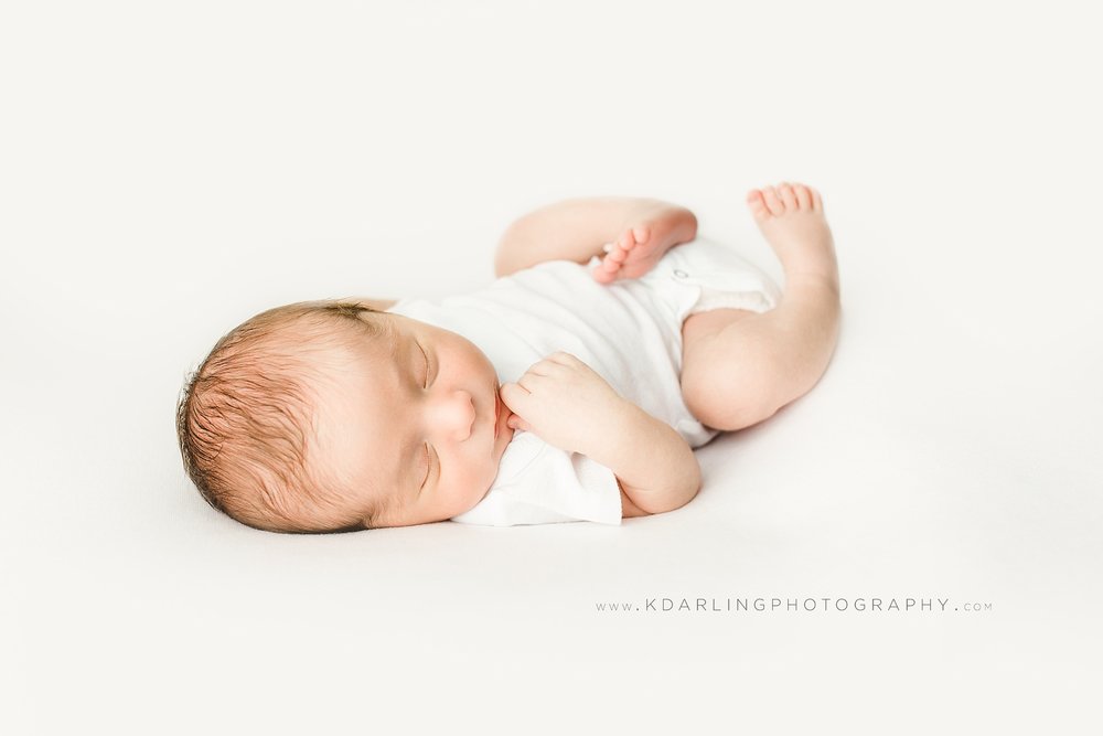 Newborn baby boy sleeping wearing white onesie