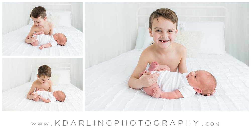 Newborn baby and brother no shirt on white bed