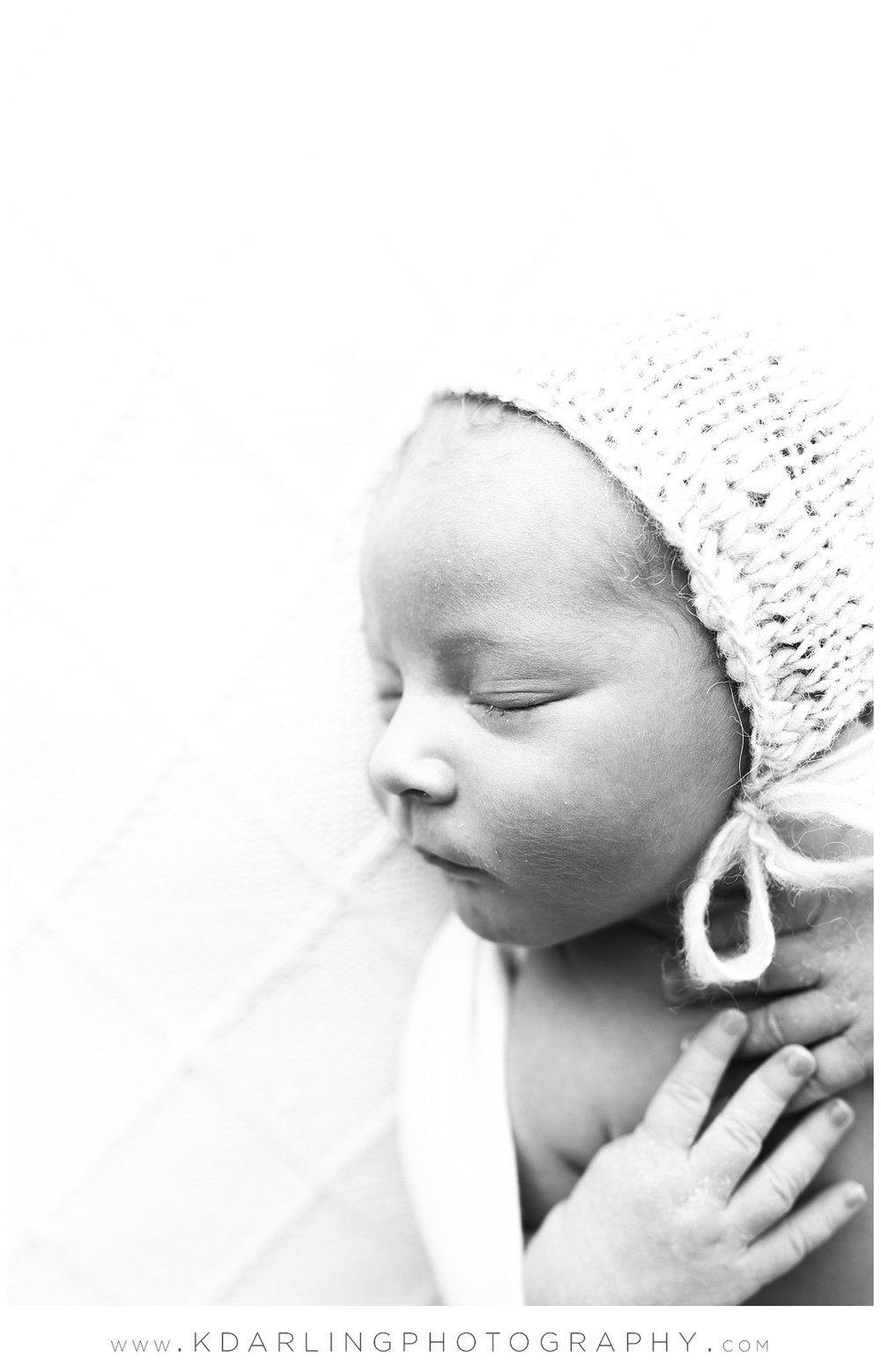 Profile of newborn baby boy wearing bonnet