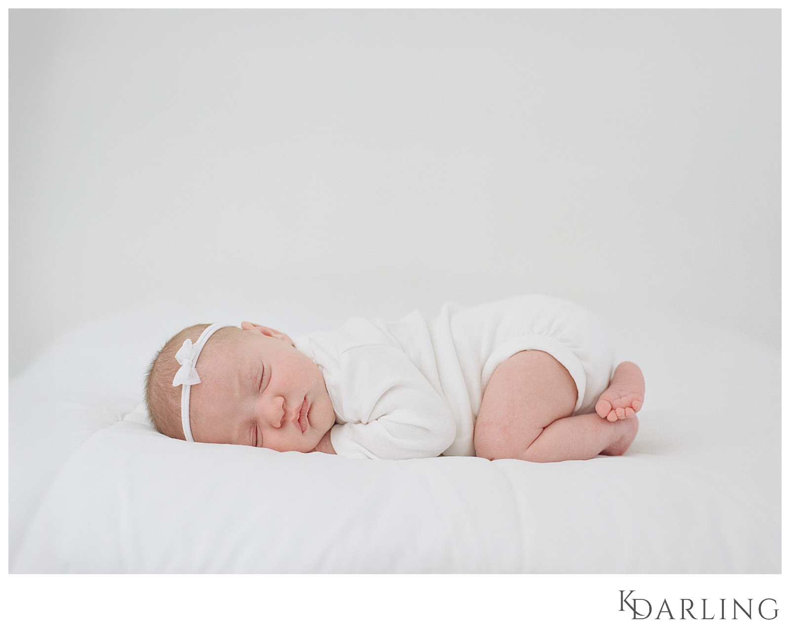 Baby in white onesie on white bed using baby led posing