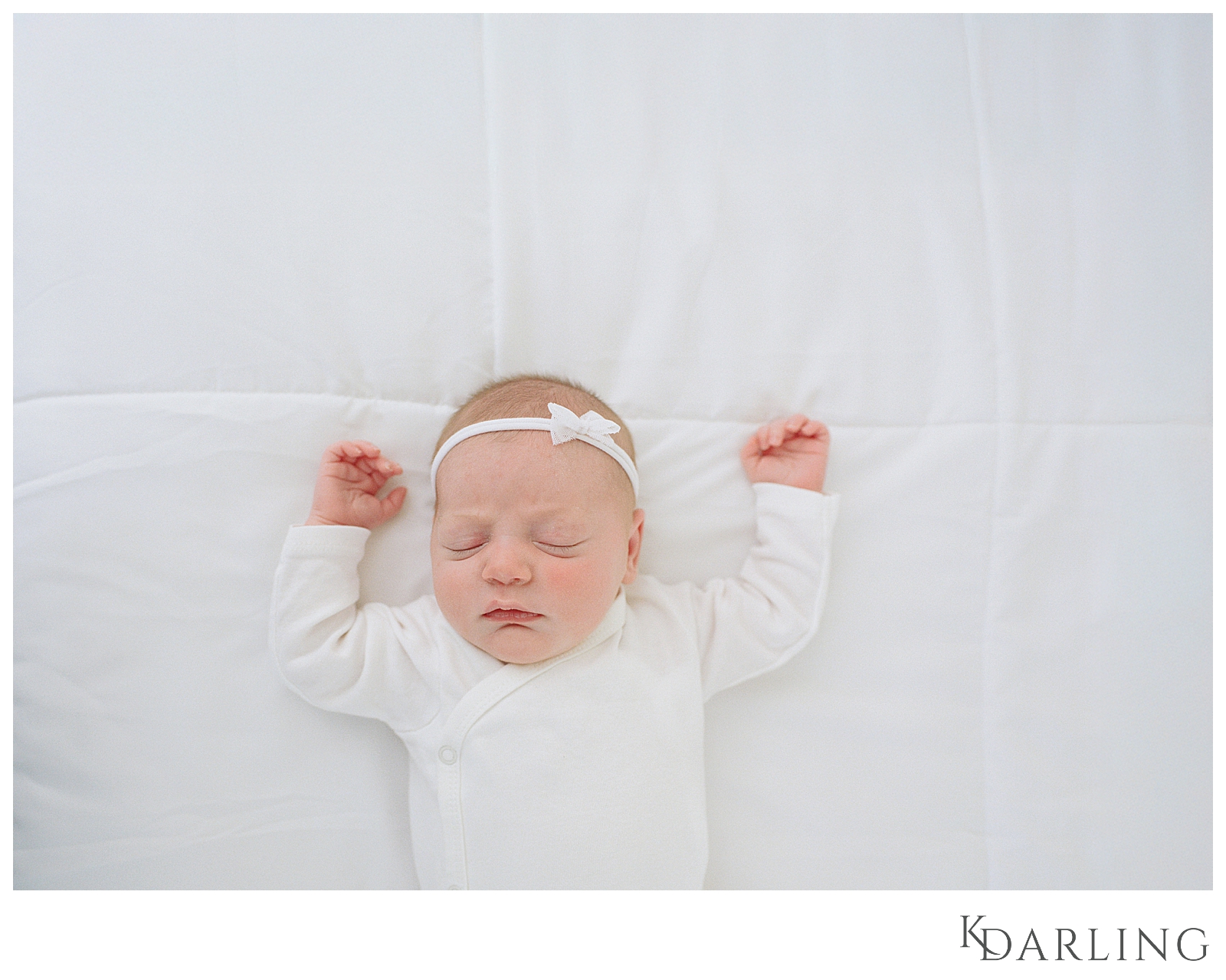 Baby in white onesie on white bed using baby led posing